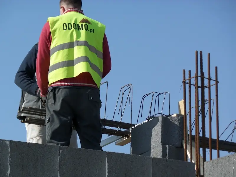 udowa domu jednorodzinnego – kontrola zbrojenia stropu przez pracownika w kamizelce Odomo.pl