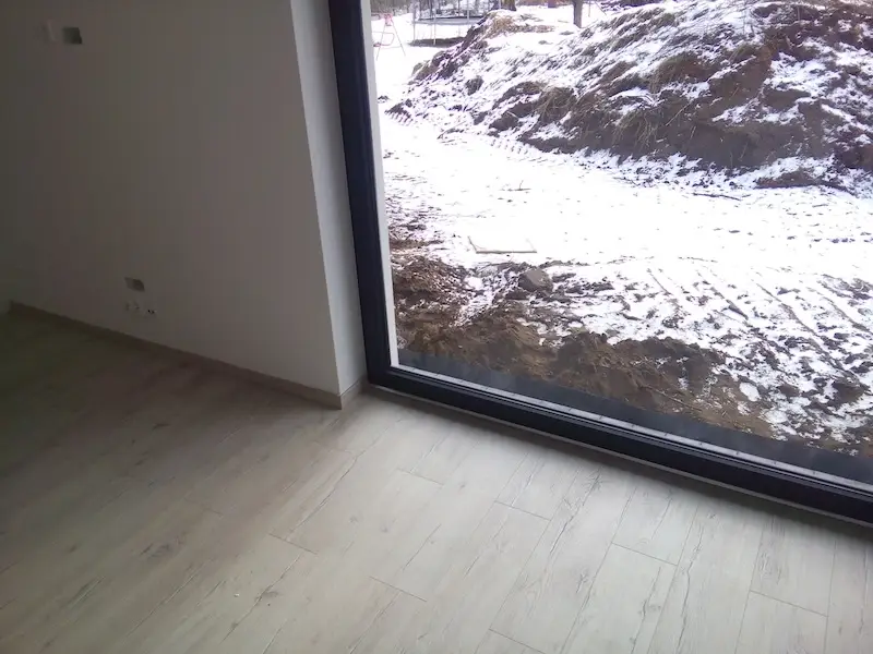 Budowa domu jednorodzinnego – widok z wnętrza na okno z roletą i ocieplonym parapetem