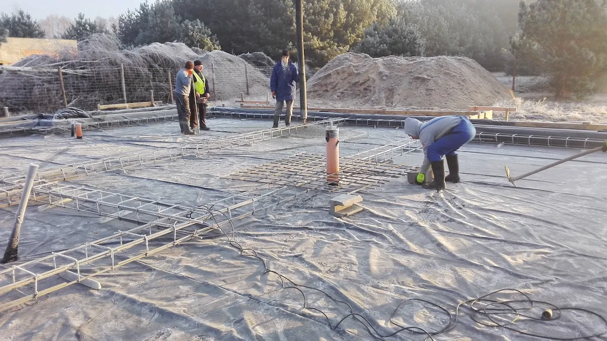 Budowa domu jednorodzinnego – ekipa Odomo.pl zacierająca i wyrównująca świeży beton na płycie
