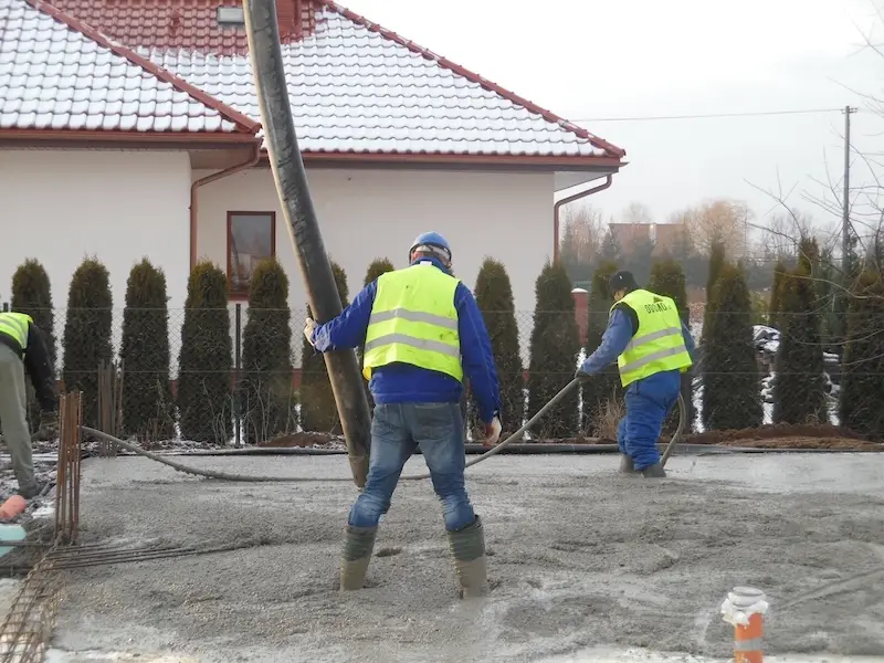 Budowa domu jednorodzinnego – rozprowadzanie betonu po płycie fundamentowej przez ekipę Odomo.pl